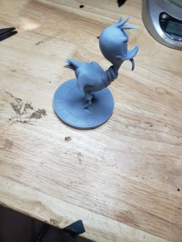 A stylized Road Runner figurine, reminiscent of the classic Looney Tunes character, 3D printed in gray resin with a circular base reading “Flip The Switch.”