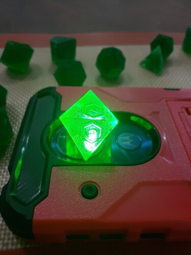 A glowing, translucent green polyhedral dice 3D printed by PlastiForge3D, showcasing unique engraving and customizable features for tabletop gaming.