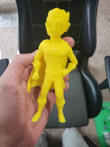 A bright yellow superhero figurine, 3D printed by PlastiForge3D using SLA technology, demonstrating custom design and high-quality 3D printing.