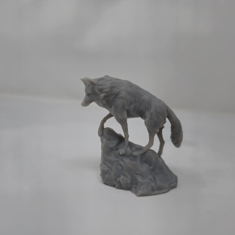 A highly detailed Snow Wolf figure in gray resin, 3D printed by PlastiForge3D and perched atop a rocky base.