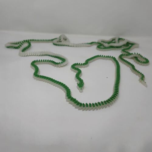 A sprawling, 10-foot 3d printed dragon figurine featuring green and translucent segments, fully 3D printed using FDM technology and laid out on a white surface.