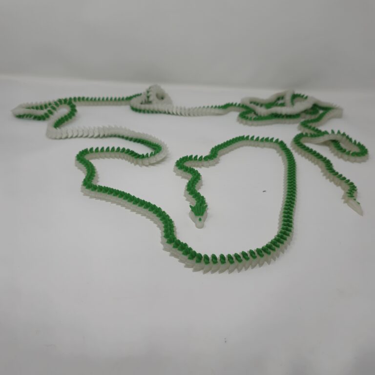 A sprawling, 10-foot 3d printed dragon figurine featuring green and translucent segments, fully 3D printed using FDM technology and laid out on a white surface.