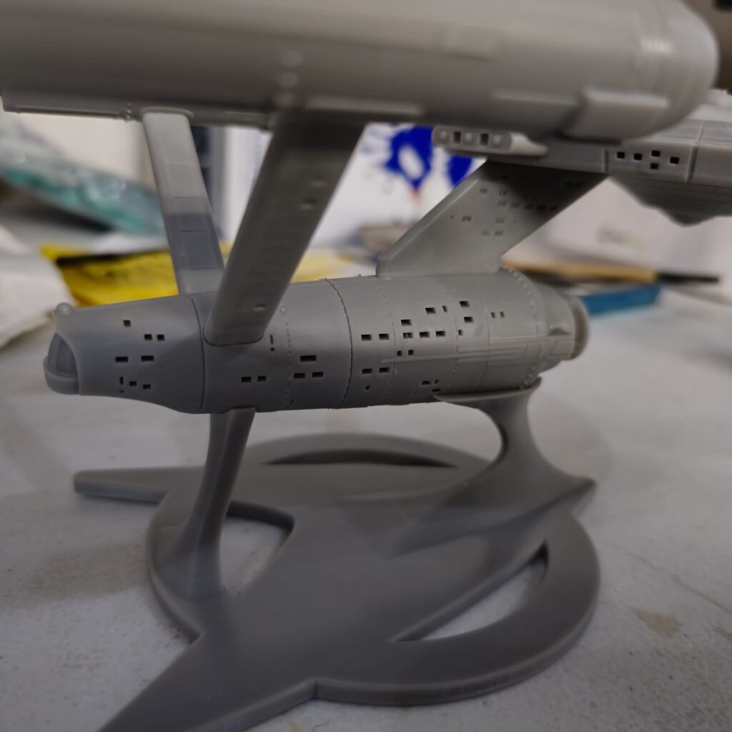 Detailed close-up of the resin-printed hull on a custom 3D printed starship model, showing window patterns and structural supports.