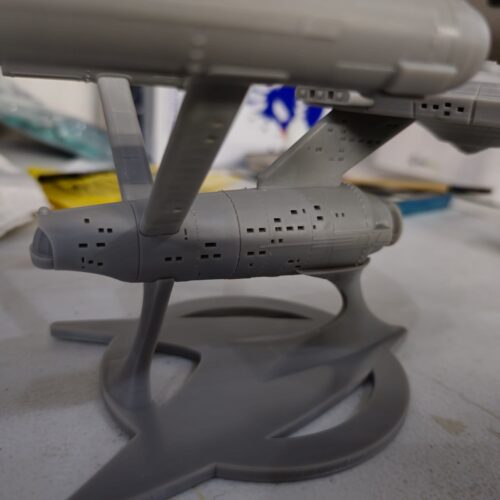 Detailed close-up of the resin-printed hull on a custom 3D printed starship model, showing window patterns and structural supports.