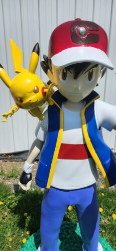 Close-up view of a life-size 3D printed statue of Ash Ketchum with Pikachu on his shoulder, showing detailed paint and craftsmanship.