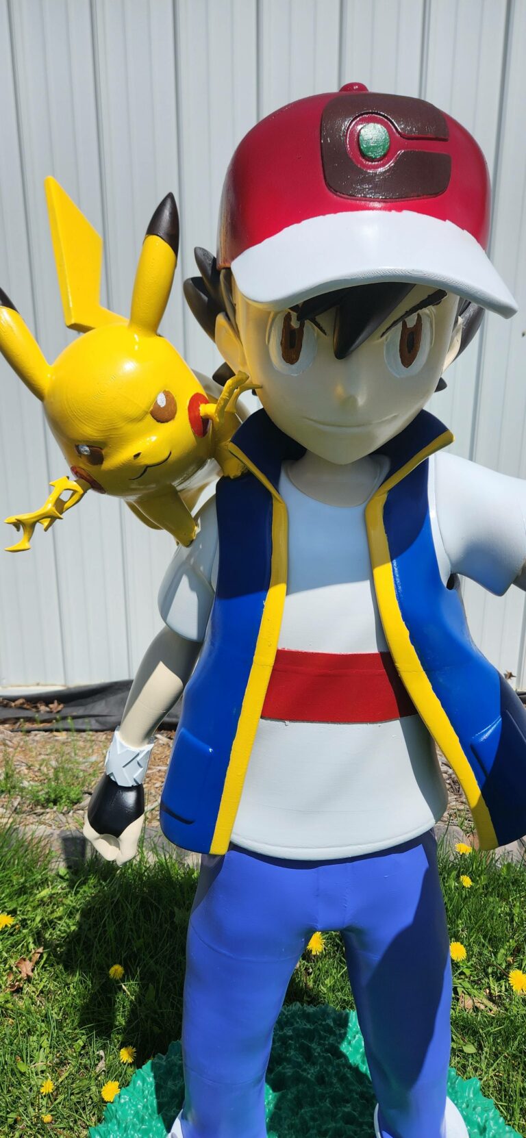 Close-up view of a life-size 3D printed statue of Ash Ketchum with Pikachu on his shoulder, showing detailed paint and craftsmanship.
