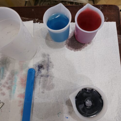 Three cups of custom mixed transparent resin in blue, red, and black, prepared for a client by PlastiForge3D.