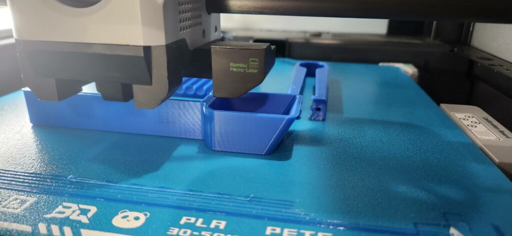 Close-up of a Bambu Lab 3D printer using Micro-Lidar for precise PETG filament printing on a blue textured build plate.