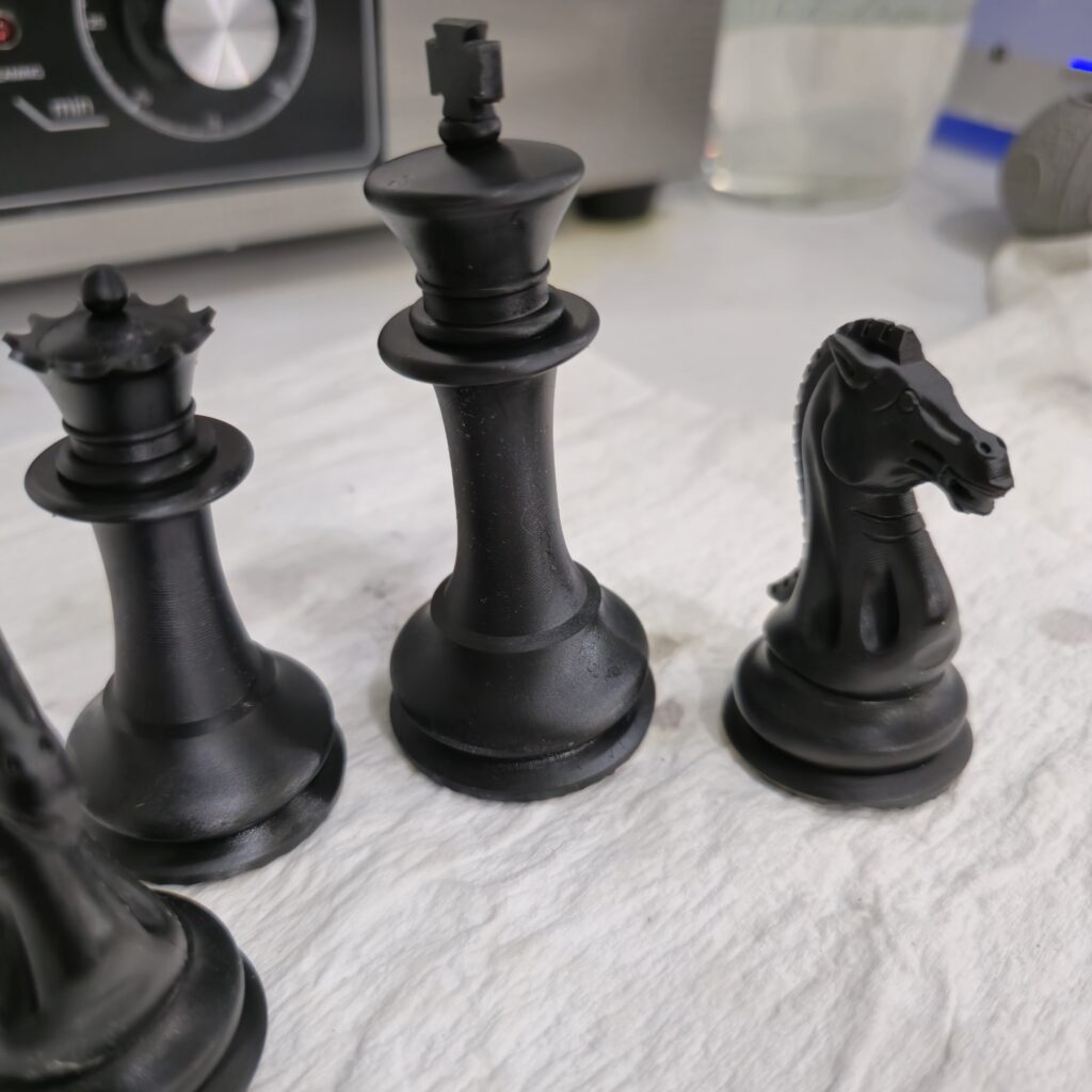 Close-up of 3D printed Staunton chess king, queen, and knight pieces in black ABS-like resin by PlastiForge3D.