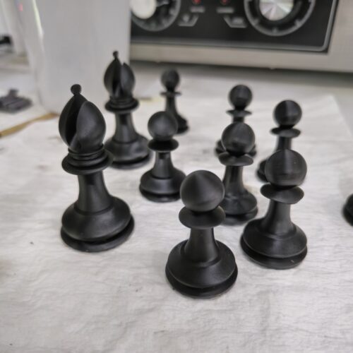 Black 3D printed Staunton chess pieces made with ABS-like resin, including bishops and pawns, printed by PlastiForge3D.